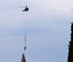 Helicopter placing statue on hilltop church